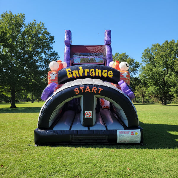 An inflatable Halloween-themed bounce house with a slide, featuring a black archway with 'Entrance' and 'START' text, purple pumpkins, and a red slide section at the top, isolated on a white background.